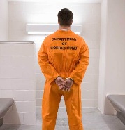 Man wearing prisoner uniform, standing in holding cell, rear view